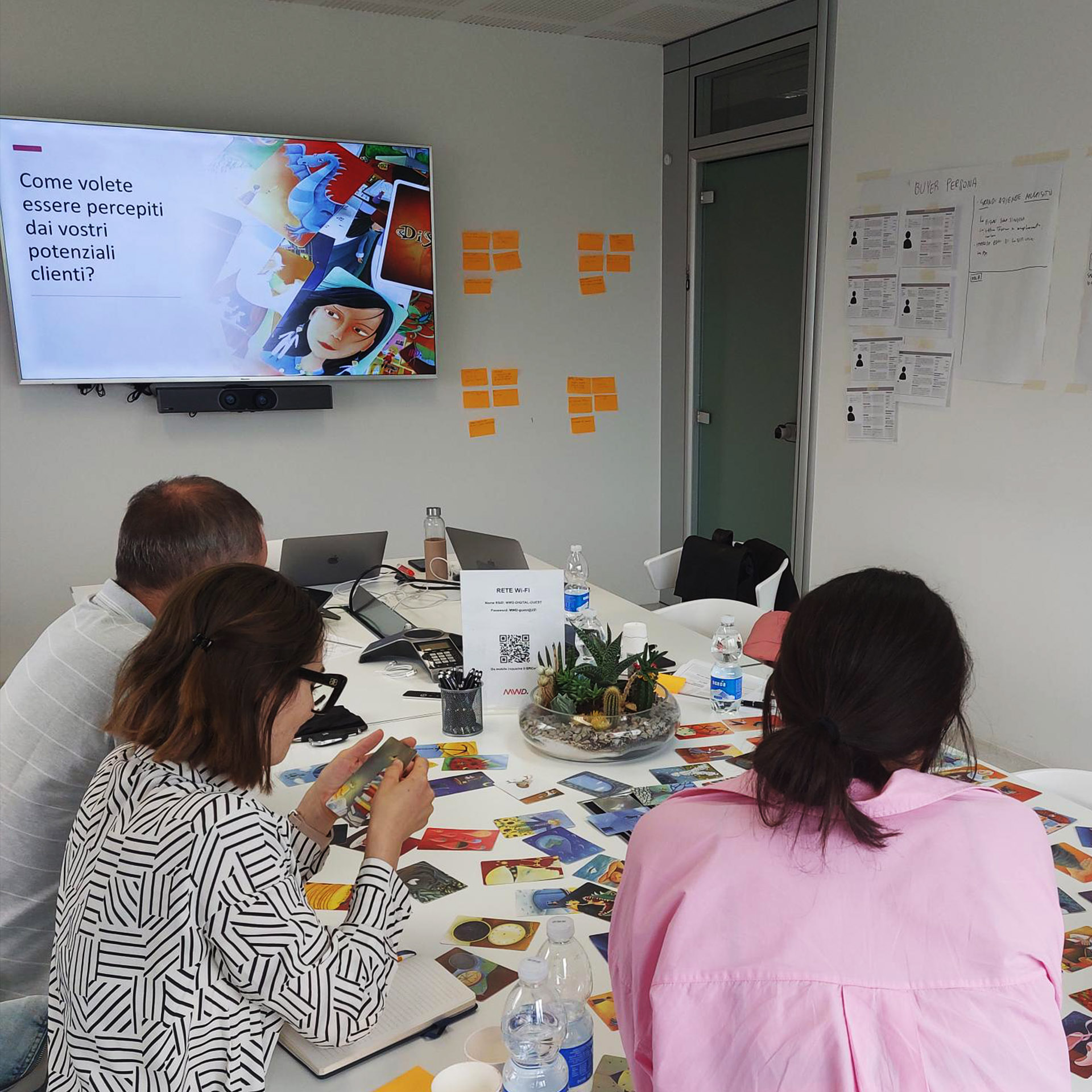 Workshop collaborativo con il team di Contec AQS: partecipanti seduti attorno a un tavolo, materiali strategici e slide proiettata per l’analisi del business e definizione del posizionamento